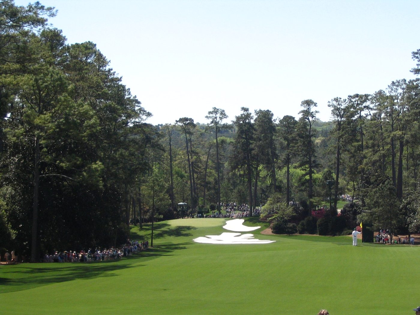 Looking down the steep 10th fairway at Augusta National with Masters patrons along the ropes