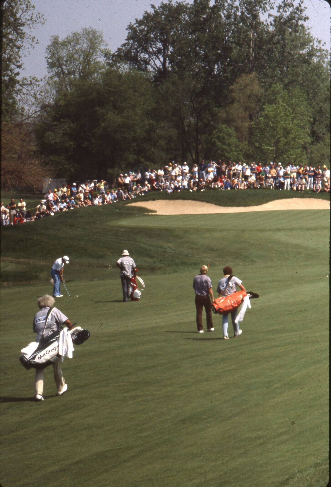 Caddies carrying tour bags down a fairway at Muirfield Village during the 1980 Memorial Tournament