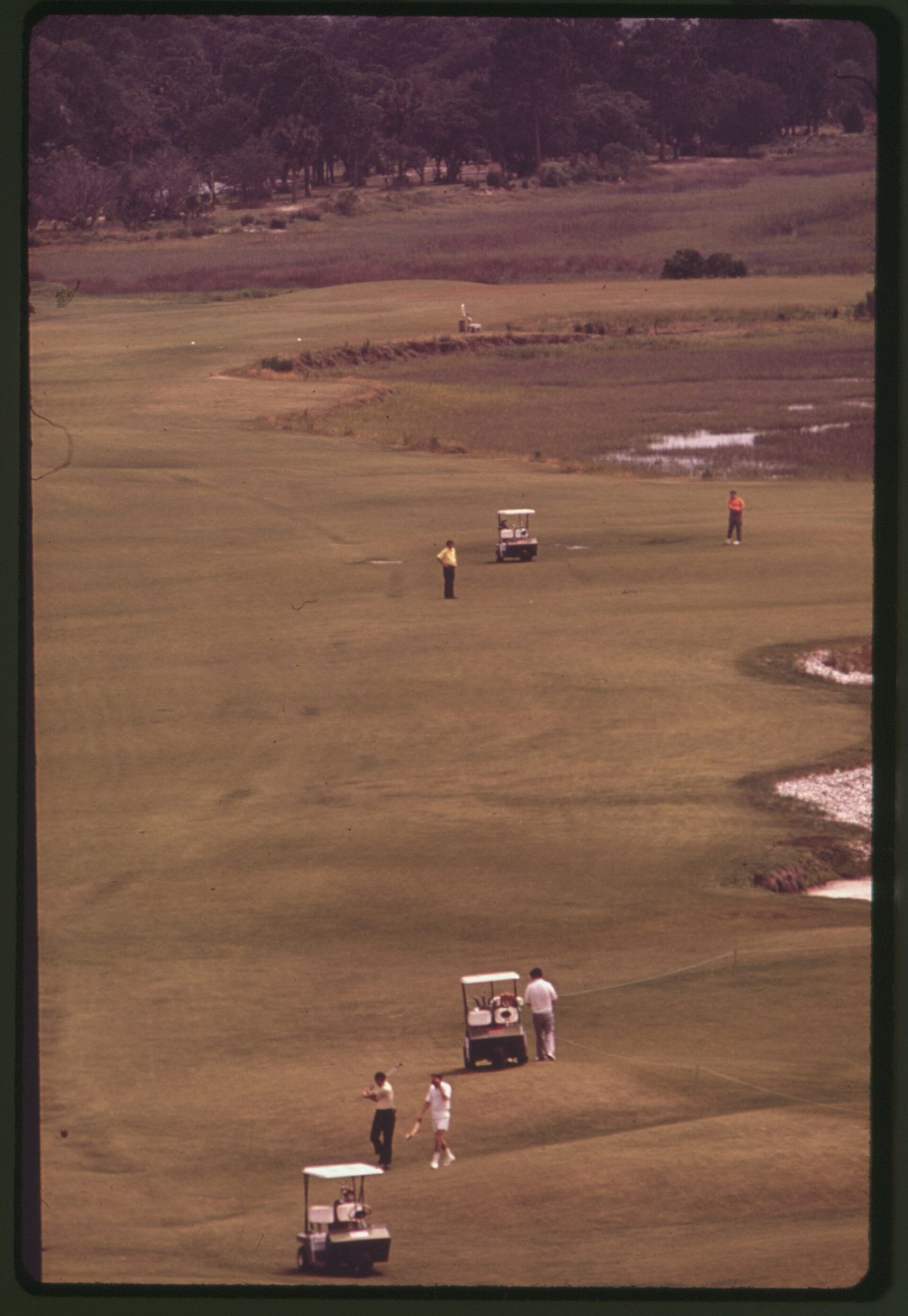 Golfers and carts on a marsh-side fairway on Hilton Head Island in an early-1970s archive photograph