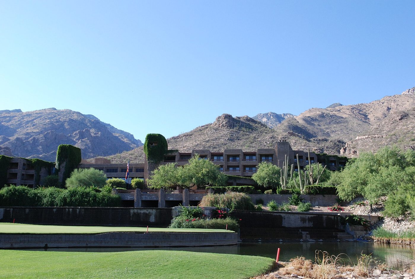 A green and pond below Loews Ventana Canyon Resort with the Santa Catalina Mountains behind, in Tucson
