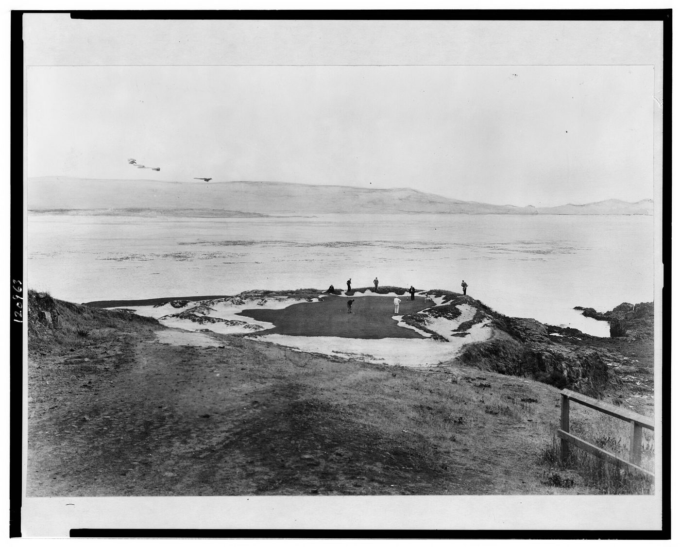 Historic photograph of golfers on the 7th green at Pebble Beach on its rocky point above Carmel Bay