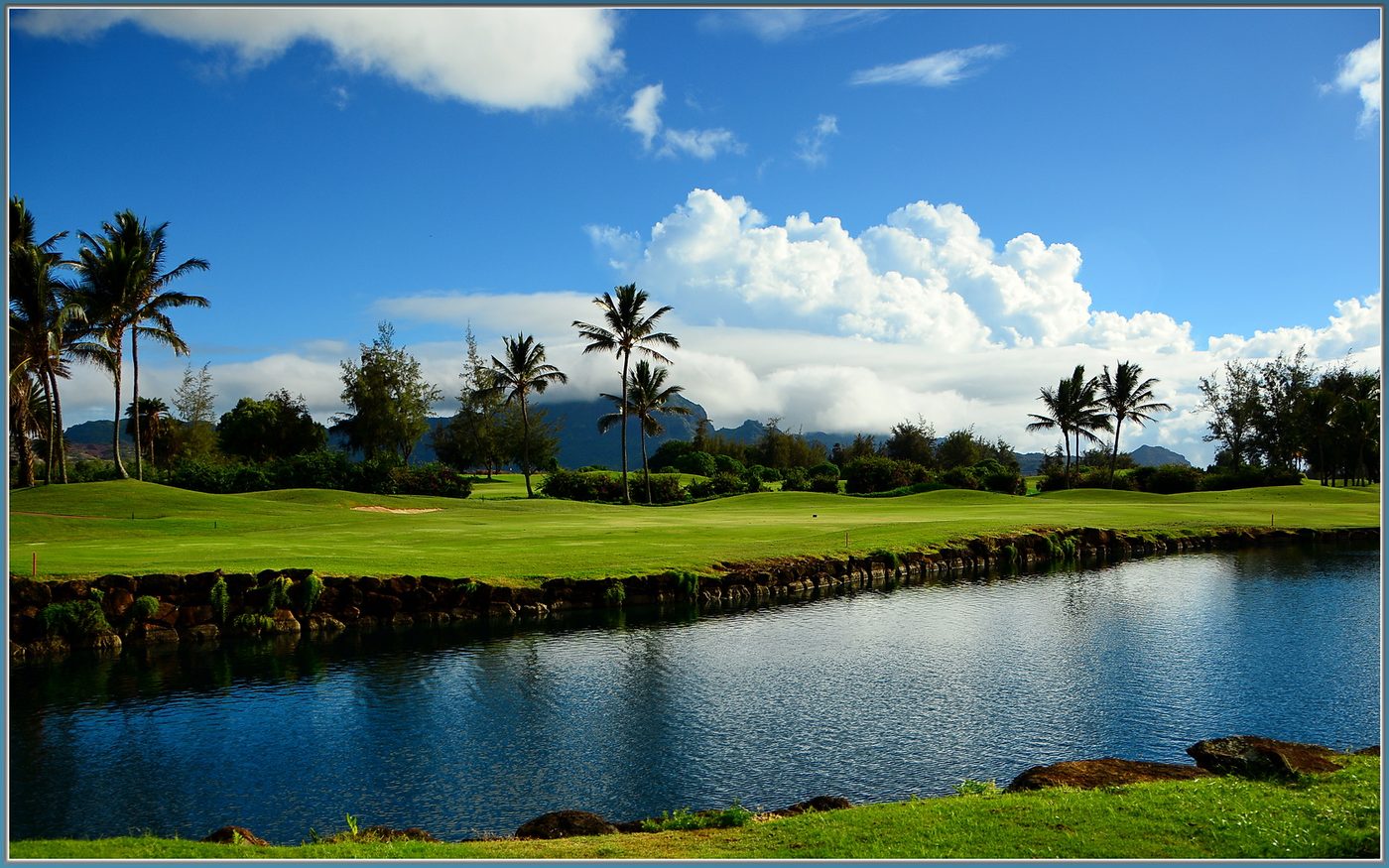 A lava-rock-lined water hazard in front of a fairway at Poipu Bay Golf Course on Kauai