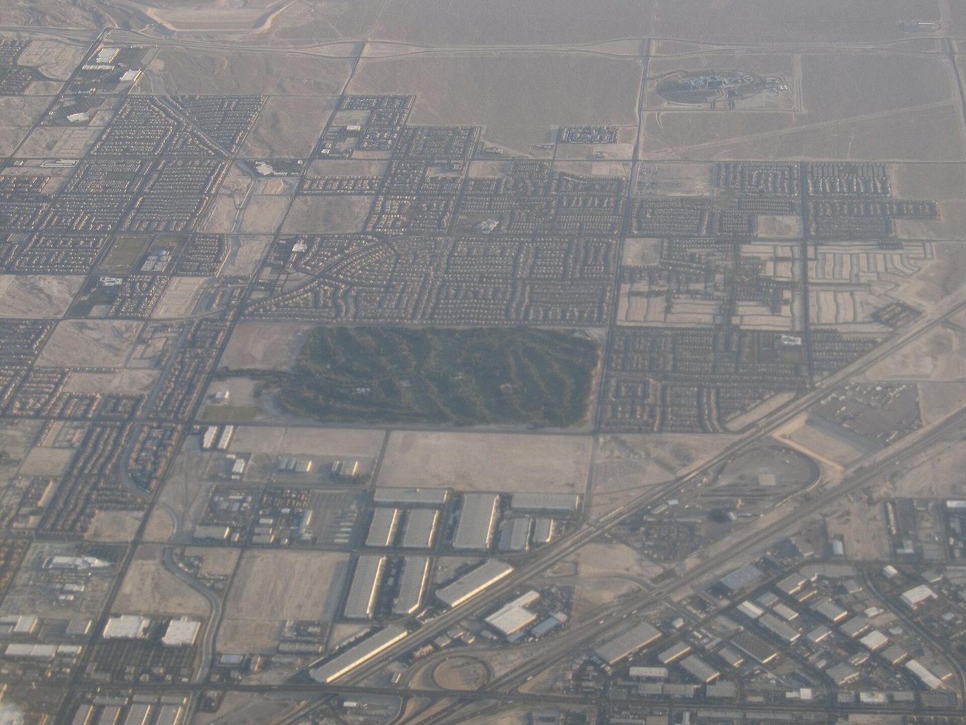 Aerial view of Shadow Creek's dark green forest of transplanted trees surrounded by the grid of North Las Vegas