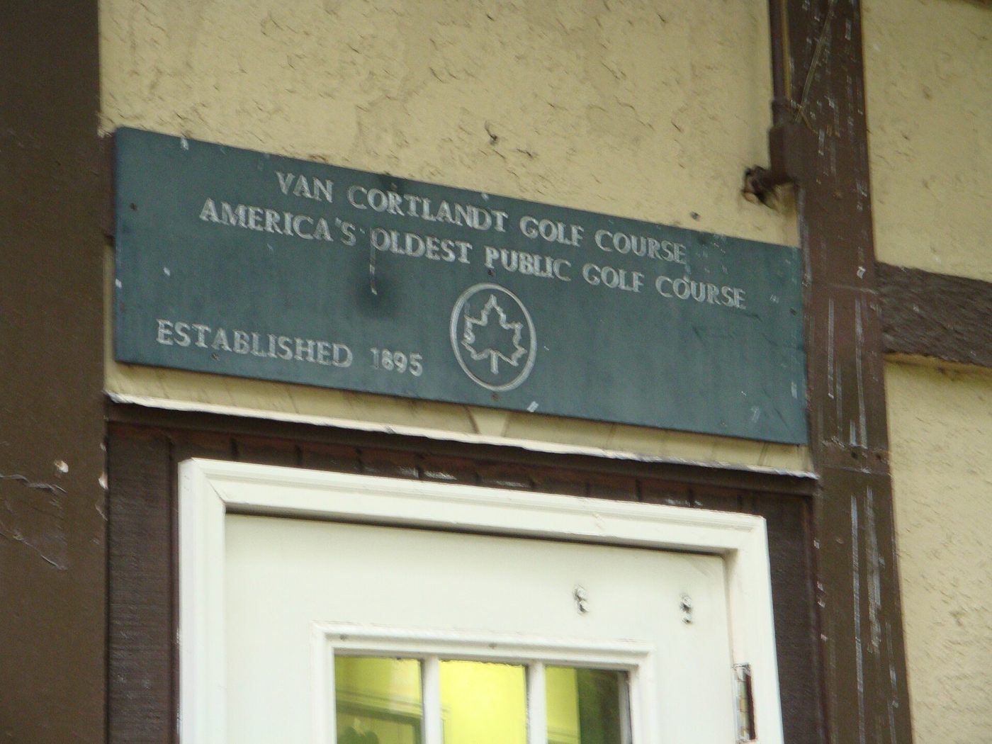 A green plaque reading Van Cortlandt Golf Course, America's oldest public golf course, established 1895