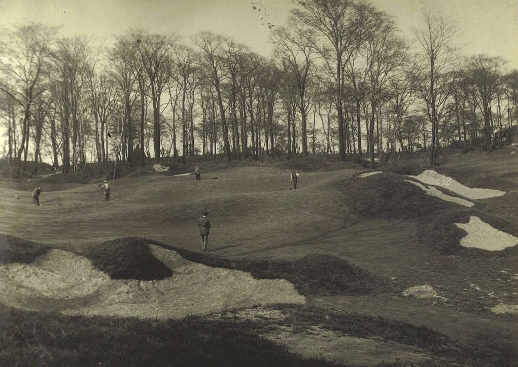 An early photograph of a par-3 green at Sitwell Park in England, designed by Alister MacKenzie, with irregular sandy bunkers in front and golfers on the green
