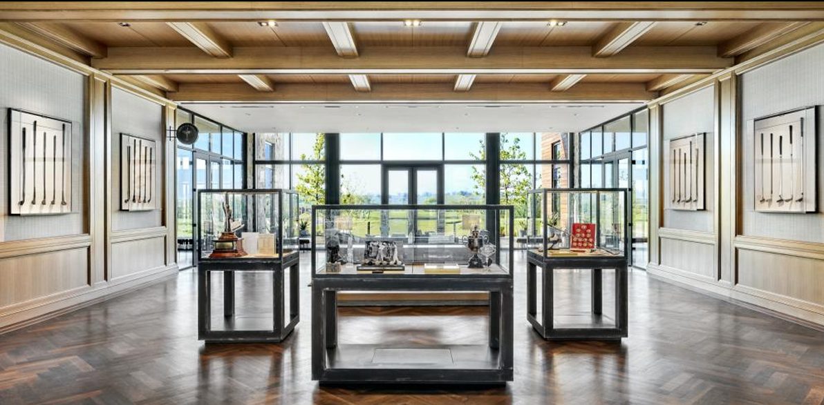 Display cases of antique golf clubs in the wood-beamed Fields Ranch clubhouse at PGA Frisco, with tall windows onto the course