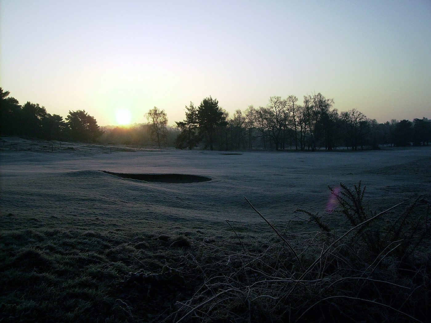 Frost covering a fairway and bunker at sunrise at Reigate Heath Golf Club in England in December