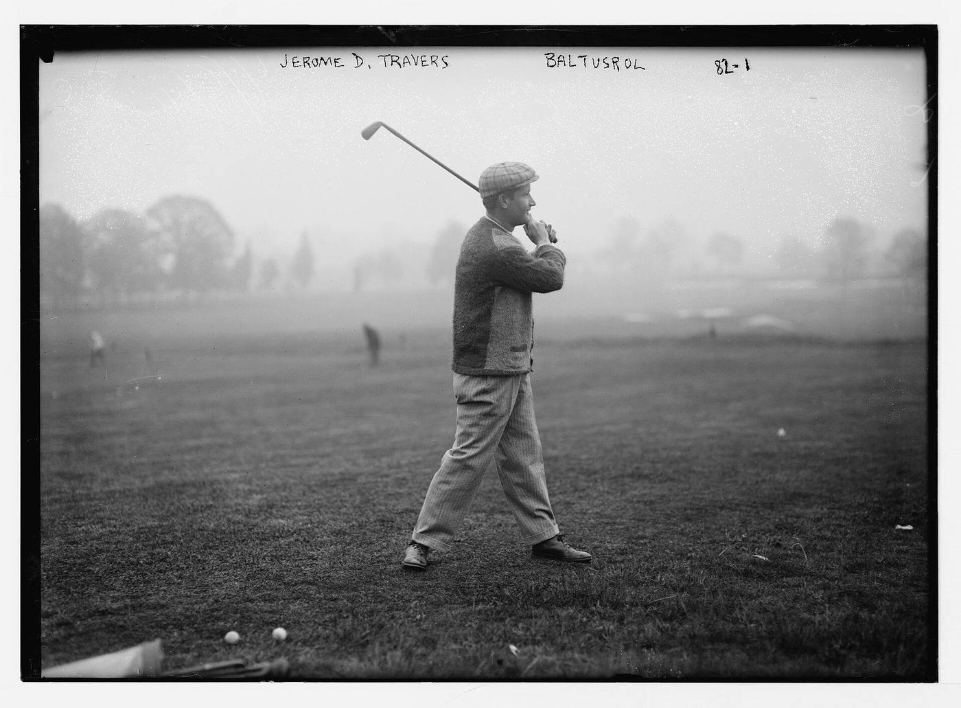 Jerome D. Travers finishing a swing on a misty fairway at Baltusrol Golf Club in a black-and-white photograph from the 1910s