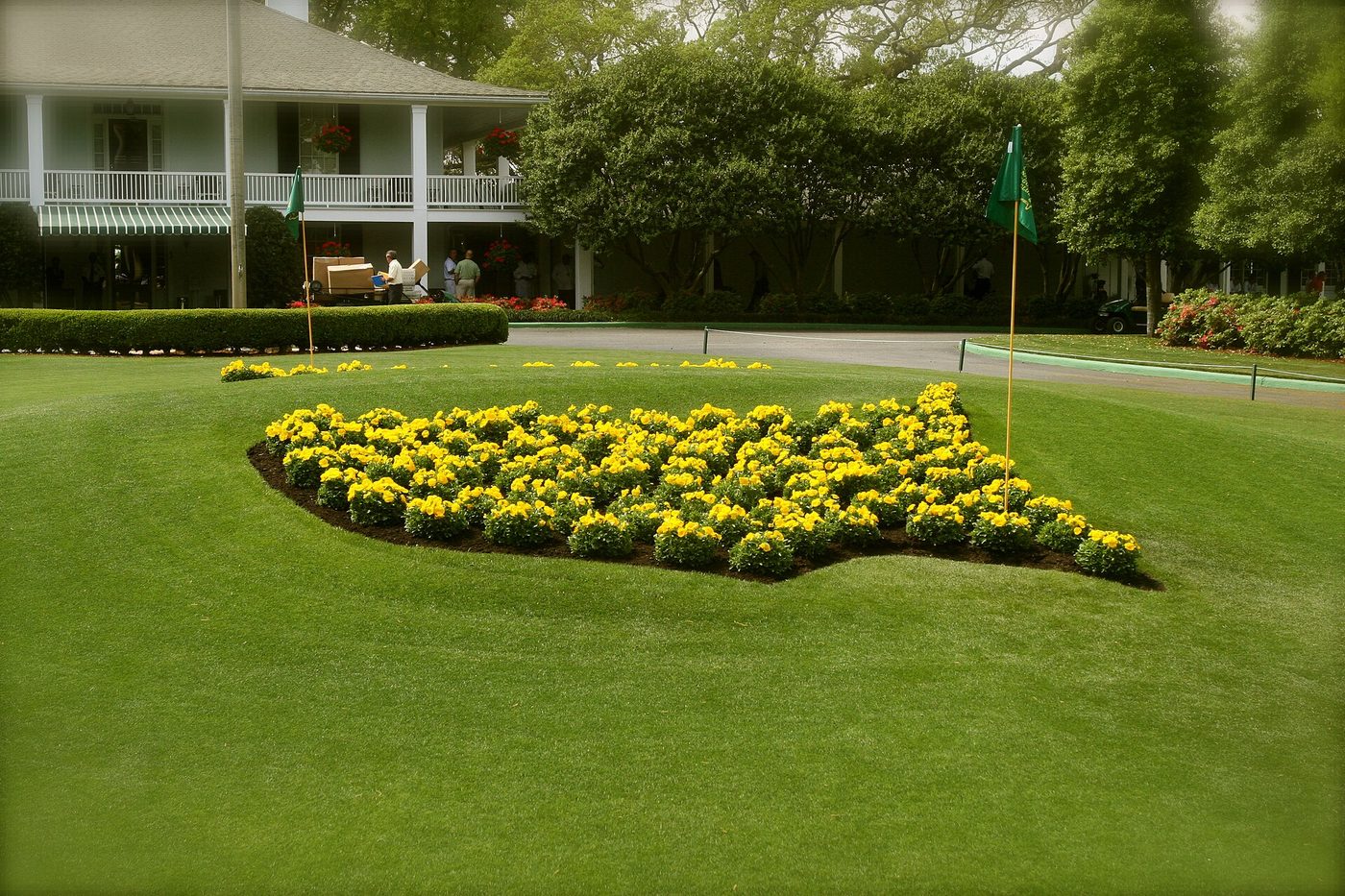The Masters logo planted in yellow flowers on the lawn in front of the white Augusta National clubhouse
