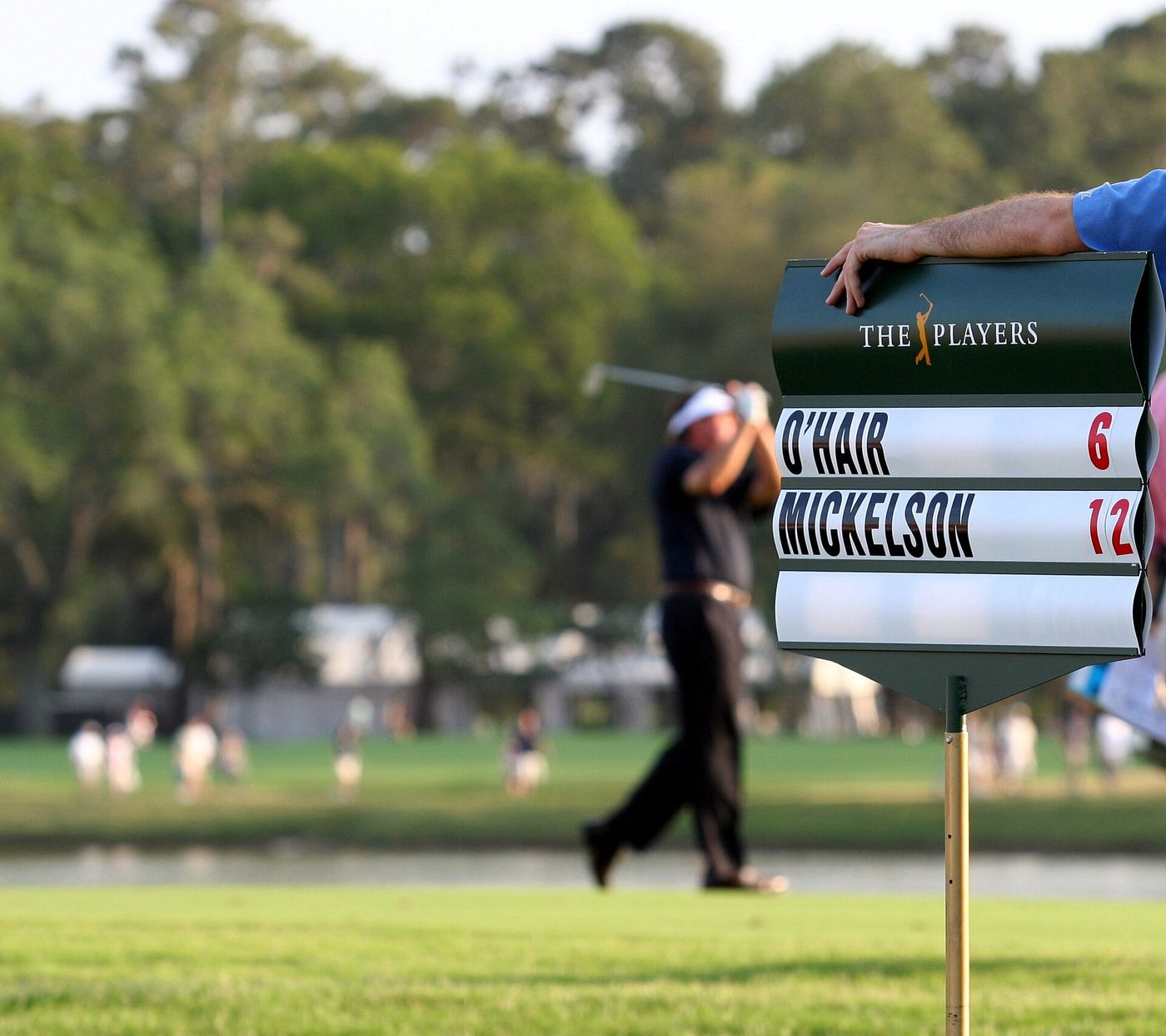 Phil Mickelson hitting his approach to the 18th green at TPC Sawgrass in the final round of the 2007 Players Championship, beside the leader board