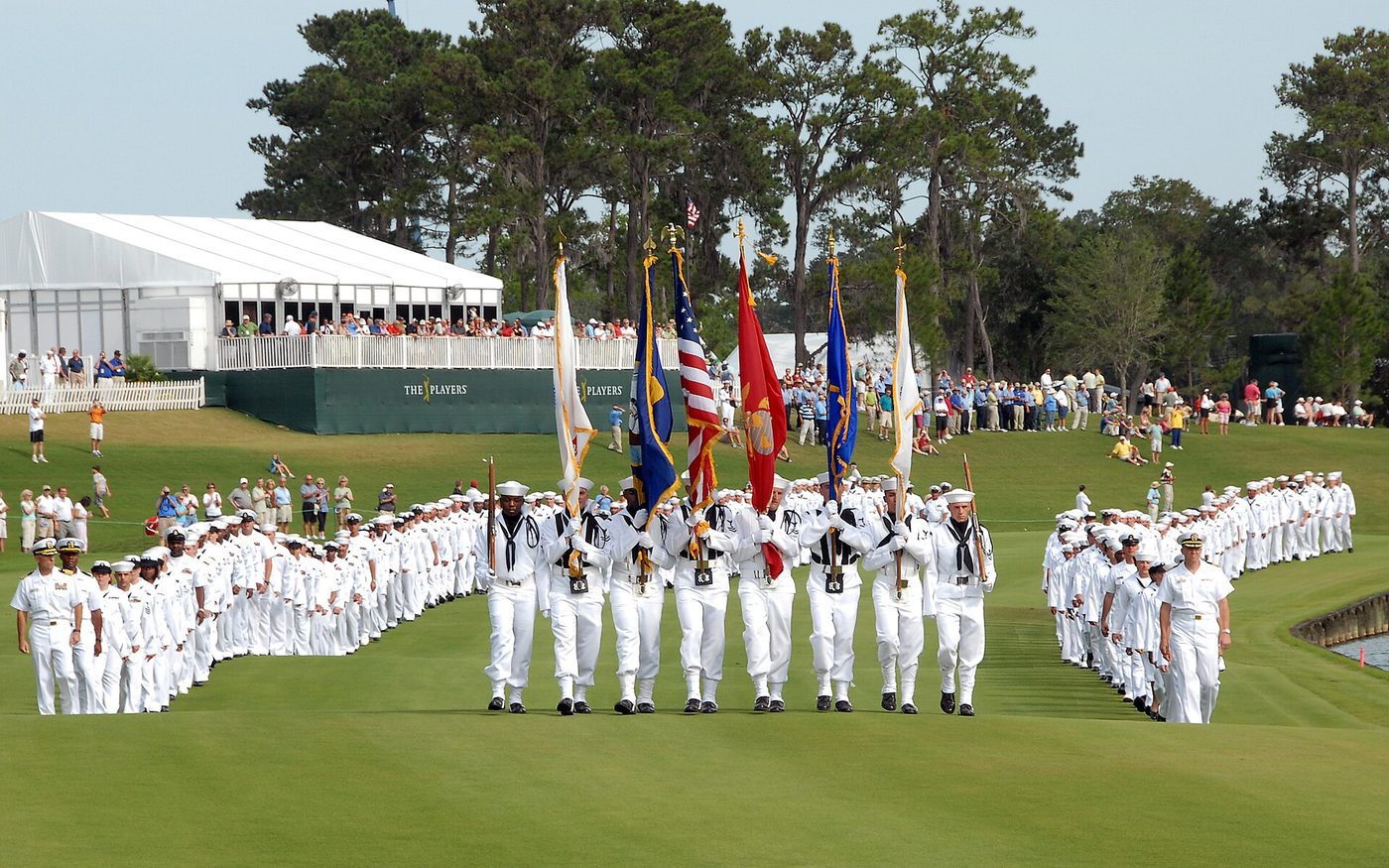 Sailors marching with flags down the 18th fairway of the TPC Sawgrass Stadium Course during the 2009 Players Championship, with hospitality grandstands behind
